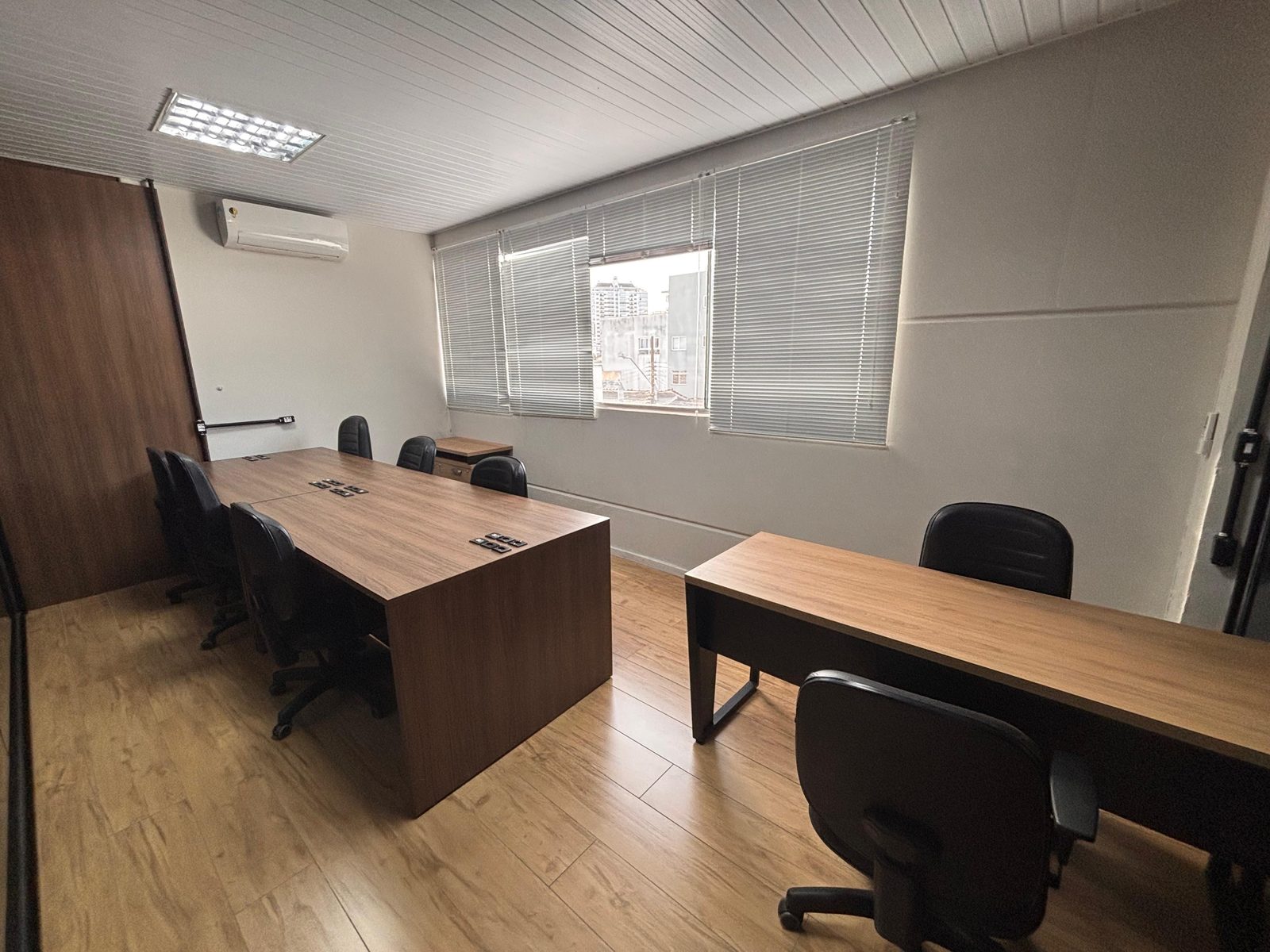 Sala de trabalho mobiliada com mesas e ar-condicionado